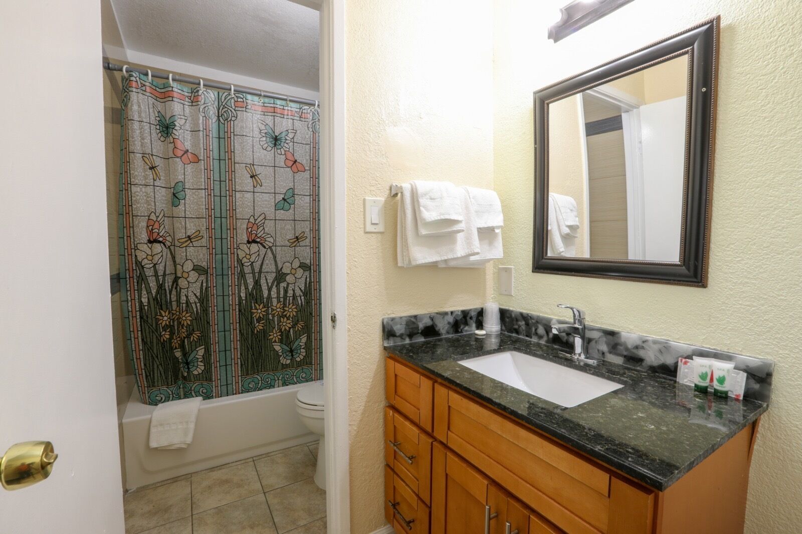 Un baño con ducha de azulejos, lavabo de mármol, armarios de madera y espejo.