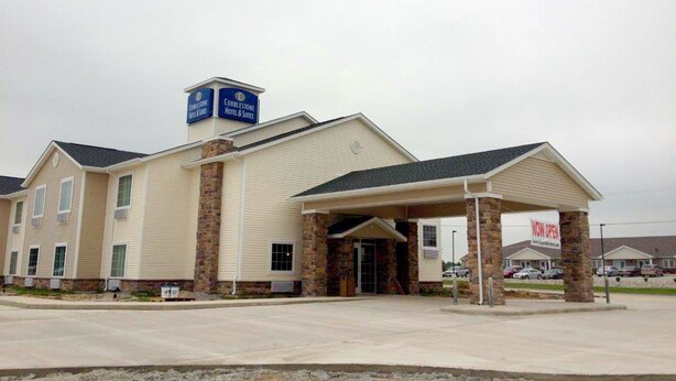 A hotel with a covered entrance, a sign indicating it is now open, and a sign for the Cobblestone Hotel & Suites. - Cobblestone Hotel & Suites - Newton (Newton)
