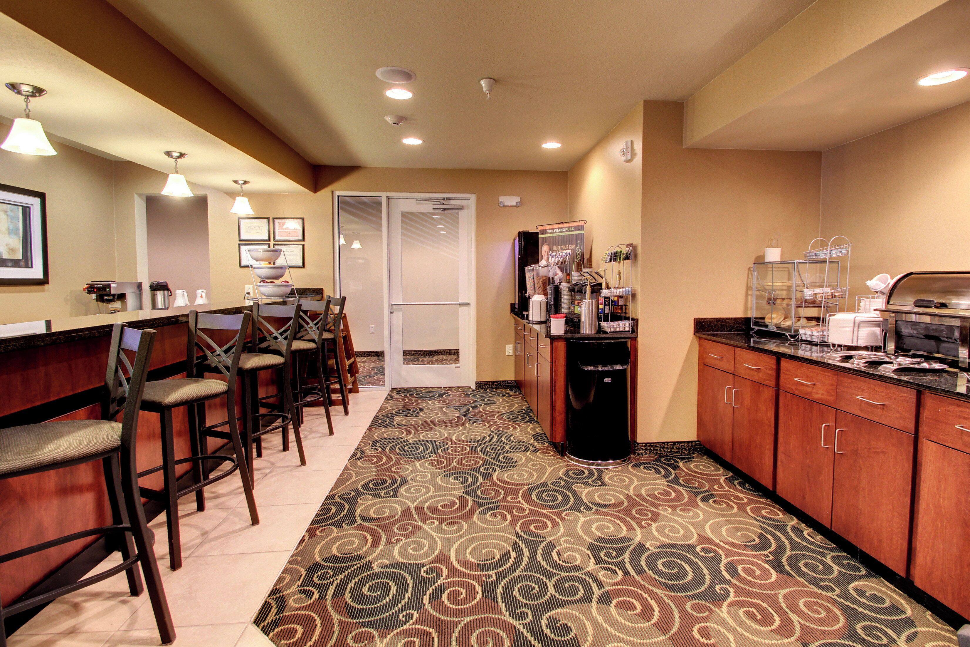 A hotel lobby with a reception desk, bar area, and seating. There are wooden cabinets and a patterned carpet.