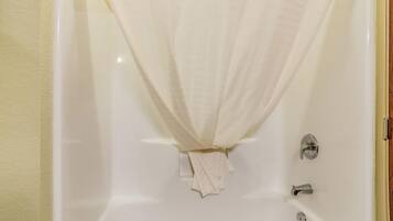 A bathtub with a white curtain and a towel hanging on the side.