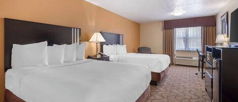 A hotel room with two beds, a desk, a chair, and a TV.