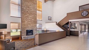 Un hall amplio con una chimenea de piedra, una recepción y una escalera que sube a los pisos superiores.