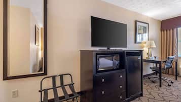 A hotel room with a flat-screen TV, a desk with a chair, a microwave, and a minibar.