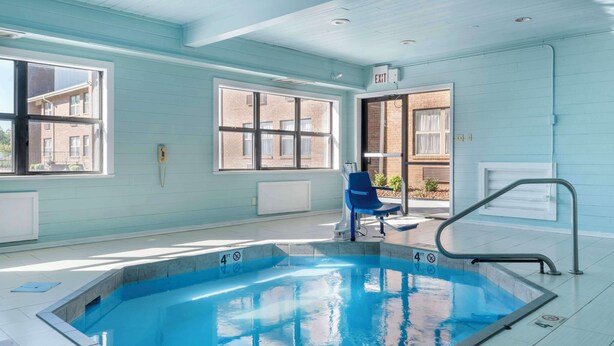 Una piscina con un indicador de profundidad de 1.2 metros, una silla azul y un pasamanos de metal.
