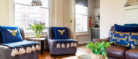 A modern living room with a sofa, two armchairs, a coffee table, and a potted plant.