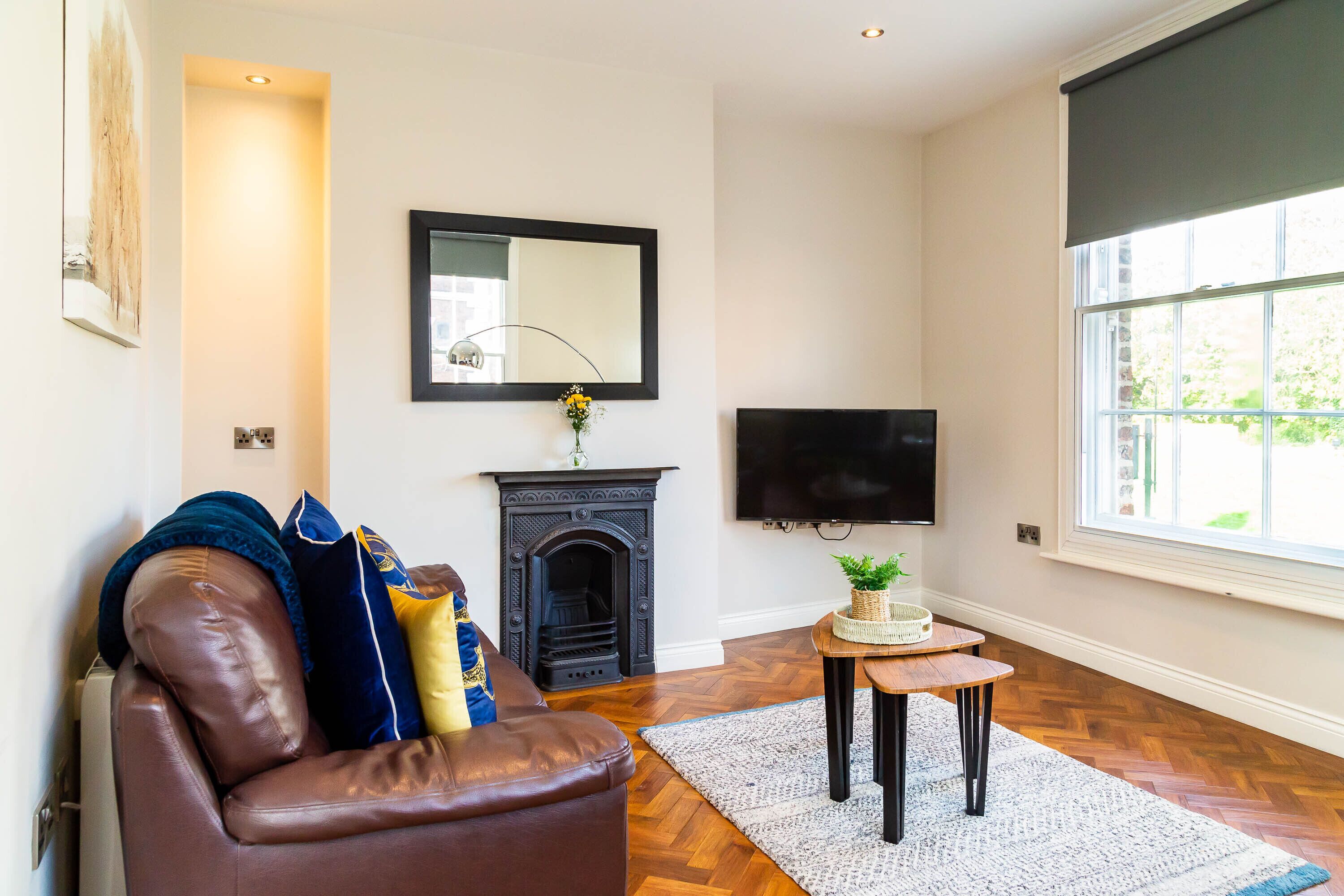 A living room with a fireplace, a sofa, a television, and a large window.