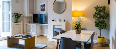 Una sala de estar moderna con un televisor de pantalla plana, una mesa de comedor con sillas, una mesa de centro y una chimenea.