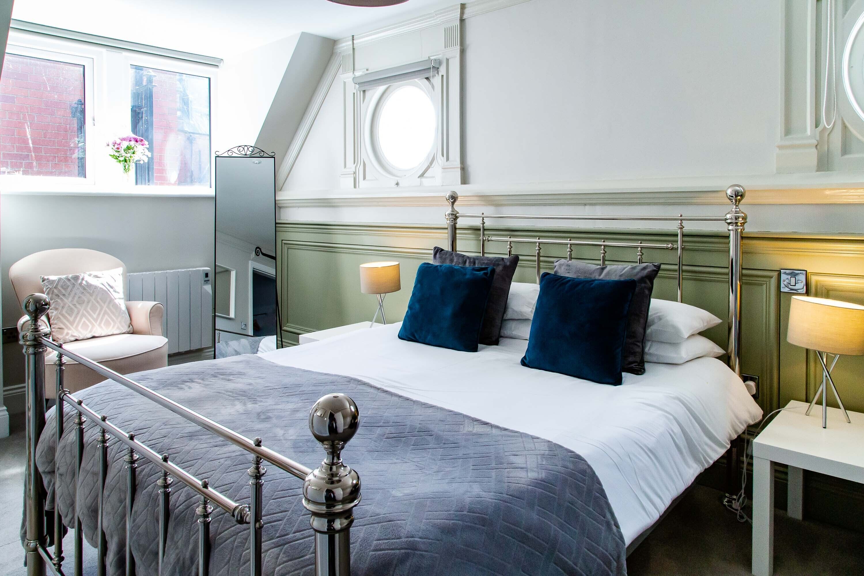 Un dormitorio ordenado con cama, mesitas de noche y una silla.