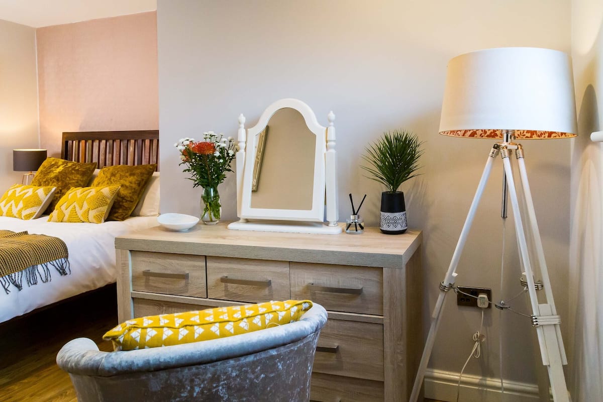 Une chambre à coucher avec un lit, une table de chevet, une lampe et un miroir.