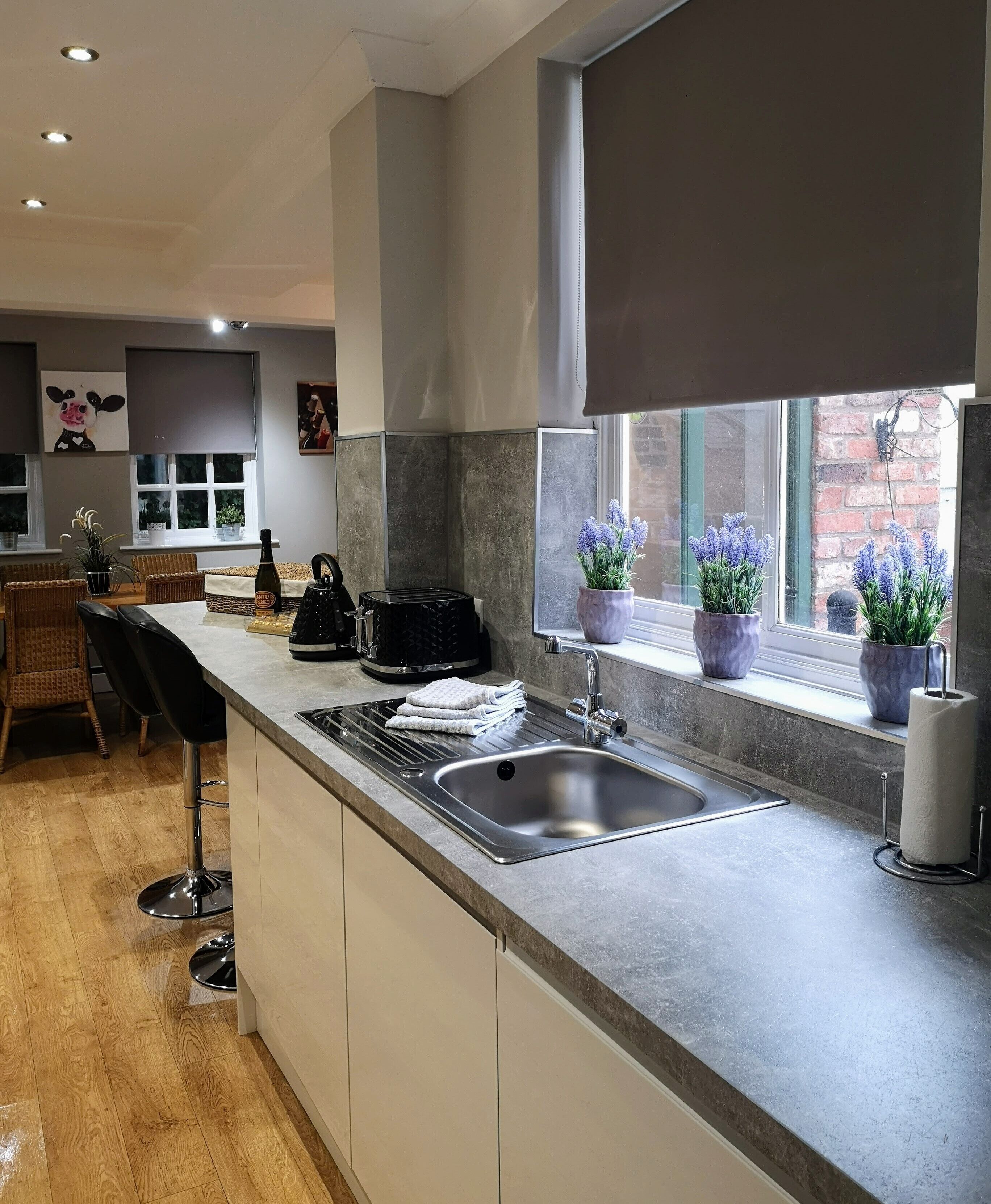 A modern kitchen with a stainless steel sink, a built-in oven, and a window with potted lavender plants.