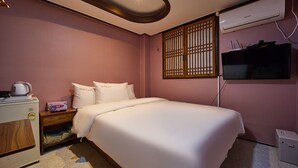 A hotel room with a bed, a nightstand, a TV, an air conditioner, and a small kitchenette. - Seoul Central Hotel (Seoul)