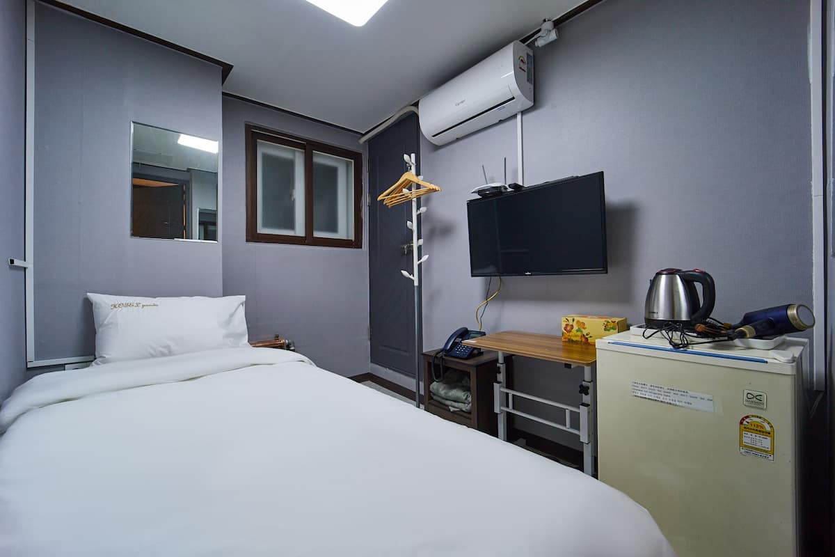 Une chambre d’hôtel équipée d’un lit, d’un bureau avec une bouilloire, d’une télévision et d’un climatiseur.