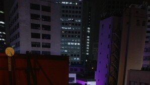A nighttime view of a cityscape with illuminated buildings and a wooden fence in the foreground. - Seoul Central Hotel (Seoul)