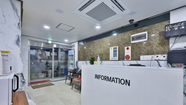 A reception area with a marble wall, a reception desk labeled "INFORMATION," and a television screen displaying a menu. - Seoul Central Hotel (Seoul)