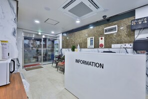 A reception area with a marble wall, a reception desk labeled "INFORMATION," and a television screen displaying a menu. - Seoul Central Hotel (Seoul)