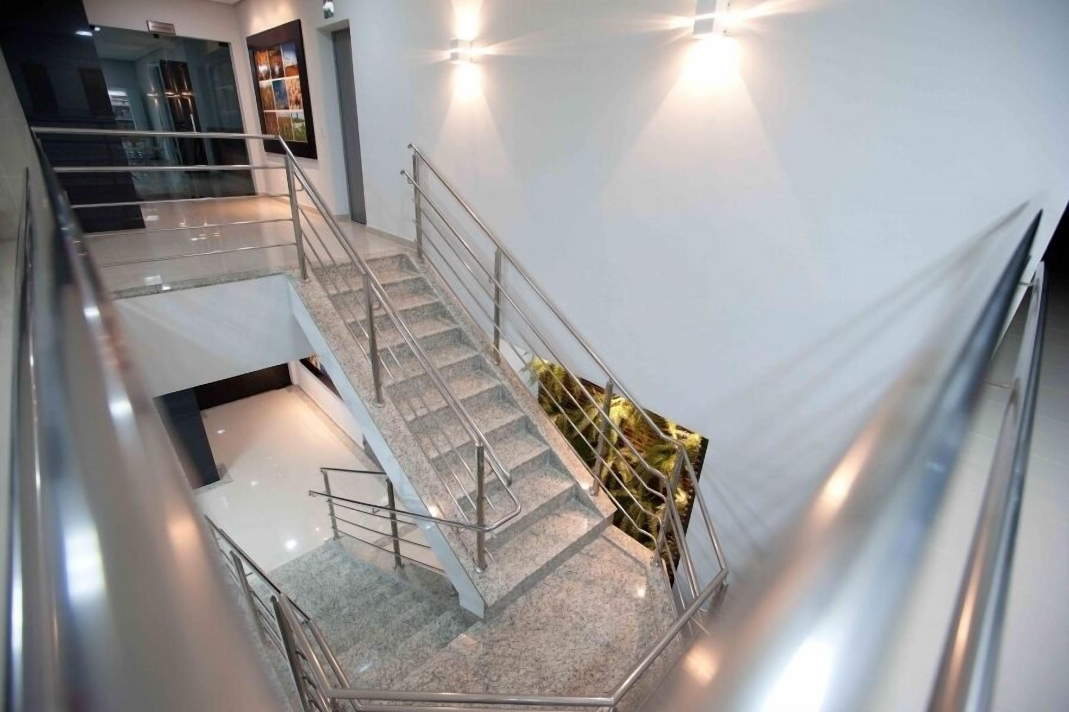 Un interior de varios niveles con escalera, barandillas de cristal y un diseño moderno.