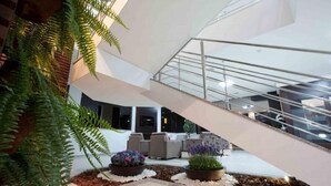 Un intérieur moderne avec un escalier, un coin salon et des plantes d’intérieur.