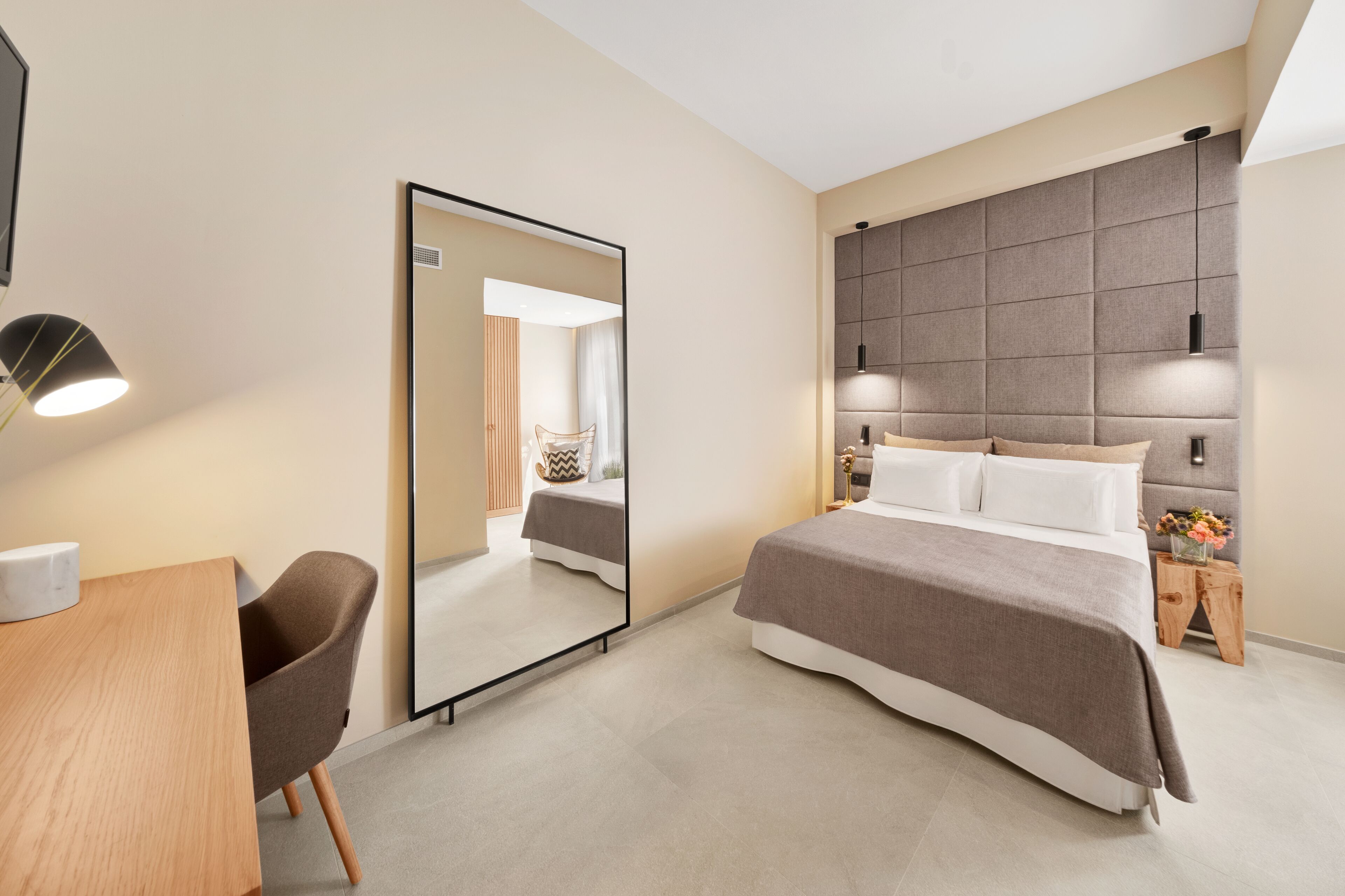 Une chambre d’hôtel moderne, dotée d’un grand lit, d’un bureau et d’un miroir.