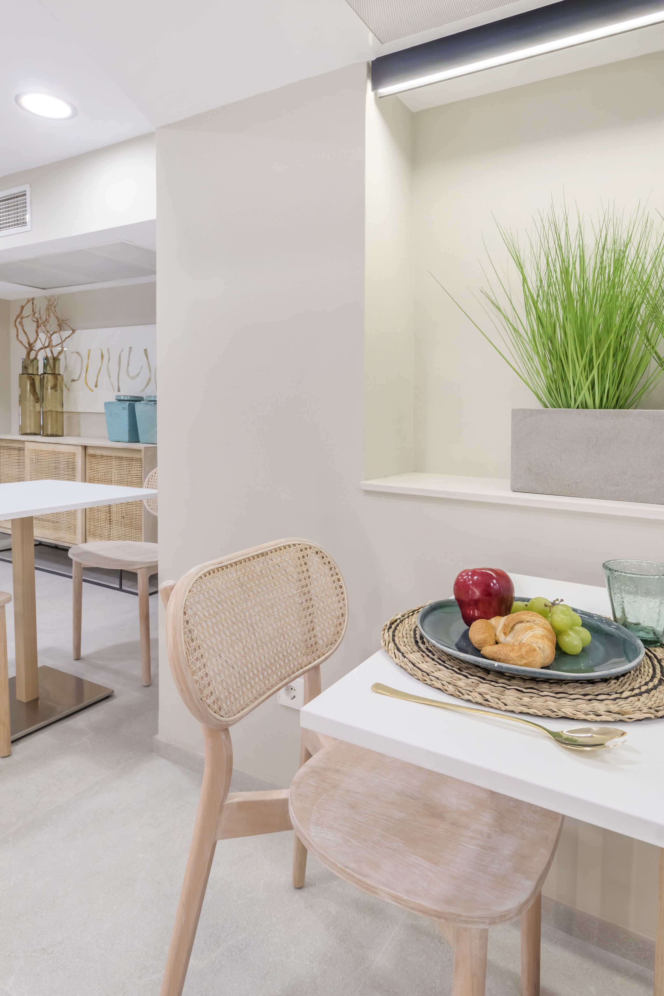 A dining area with a white table, wicker chairs, and a plate of fruit.