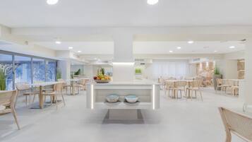 A modern dining area with a central island, multiple seating arrangements, and a view of the outdoors.