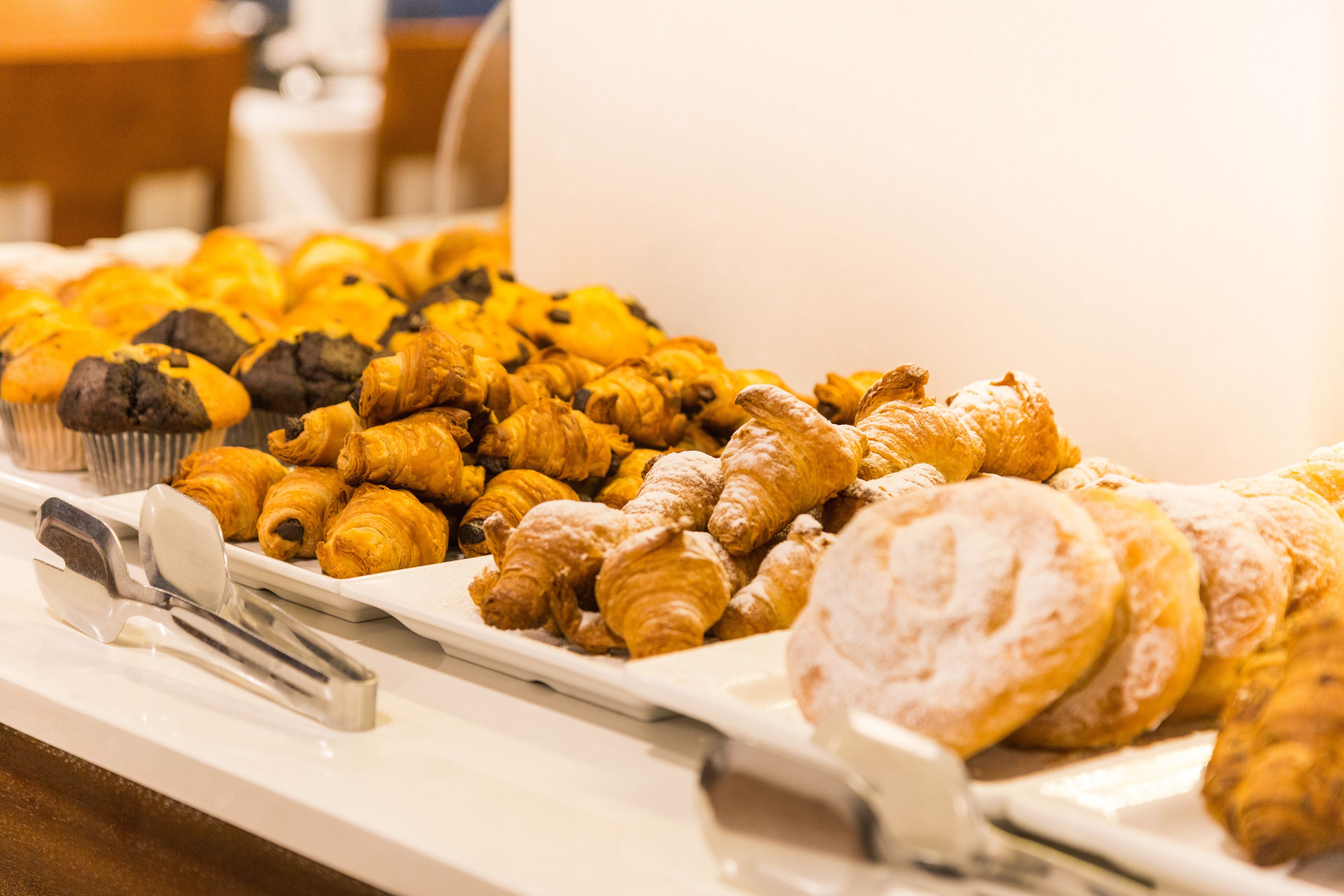Un bufé con diversos pasteles, incluyendo cruasanes y muffins.