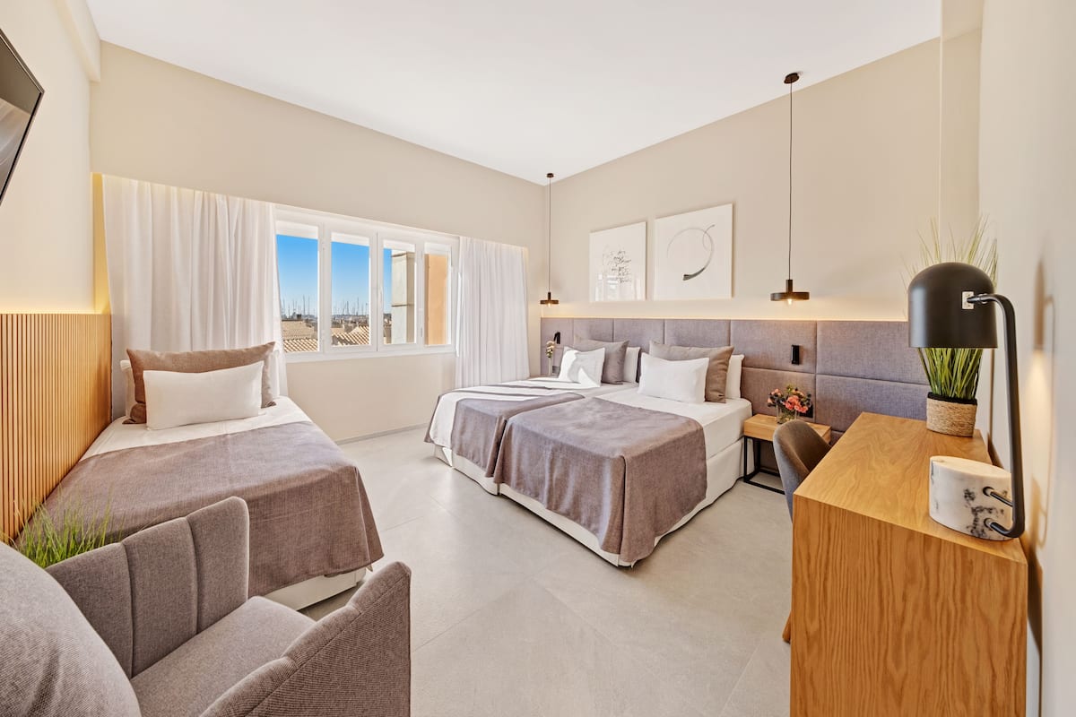 A modern hotel room with a large bed, two bedside tables, a desk, and a view of the city.