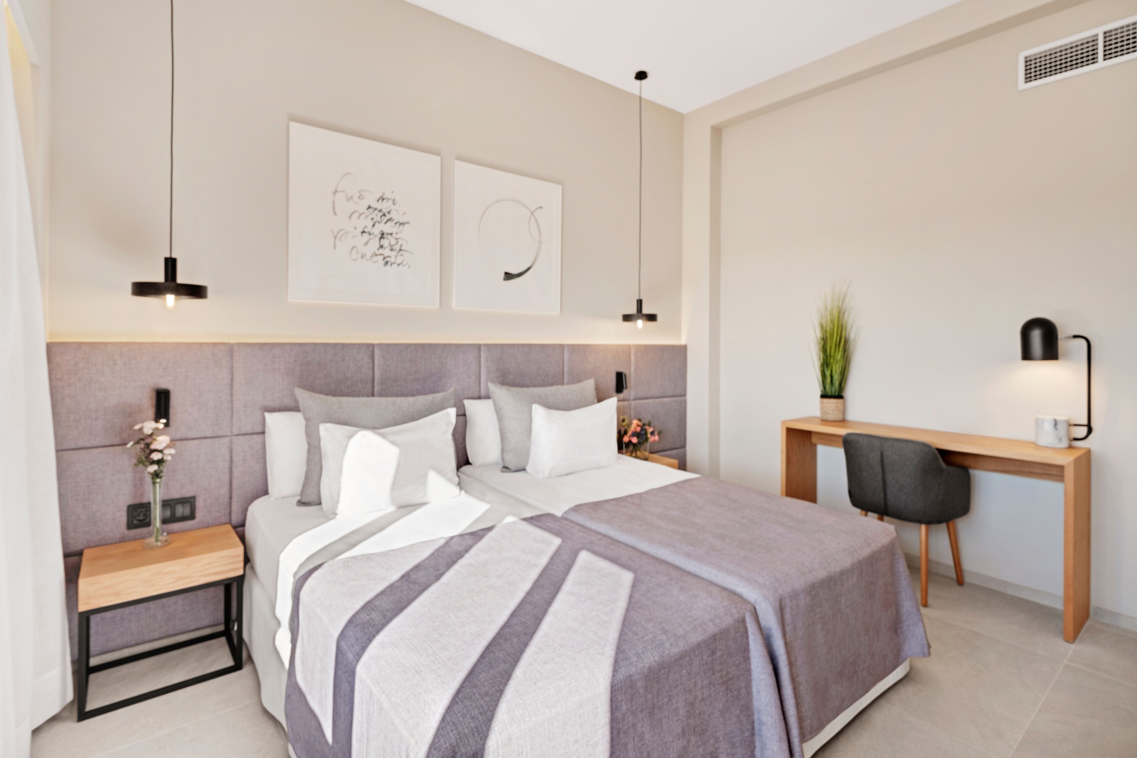 A modern bedroom with a large bed, bedside tables, a desk, and a chair.