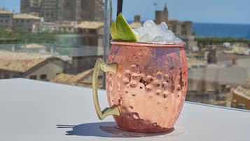 Ein Kupferbecher mit Trinkhalm und Limette auf einem Balkon mit Blick auf die Stadt.