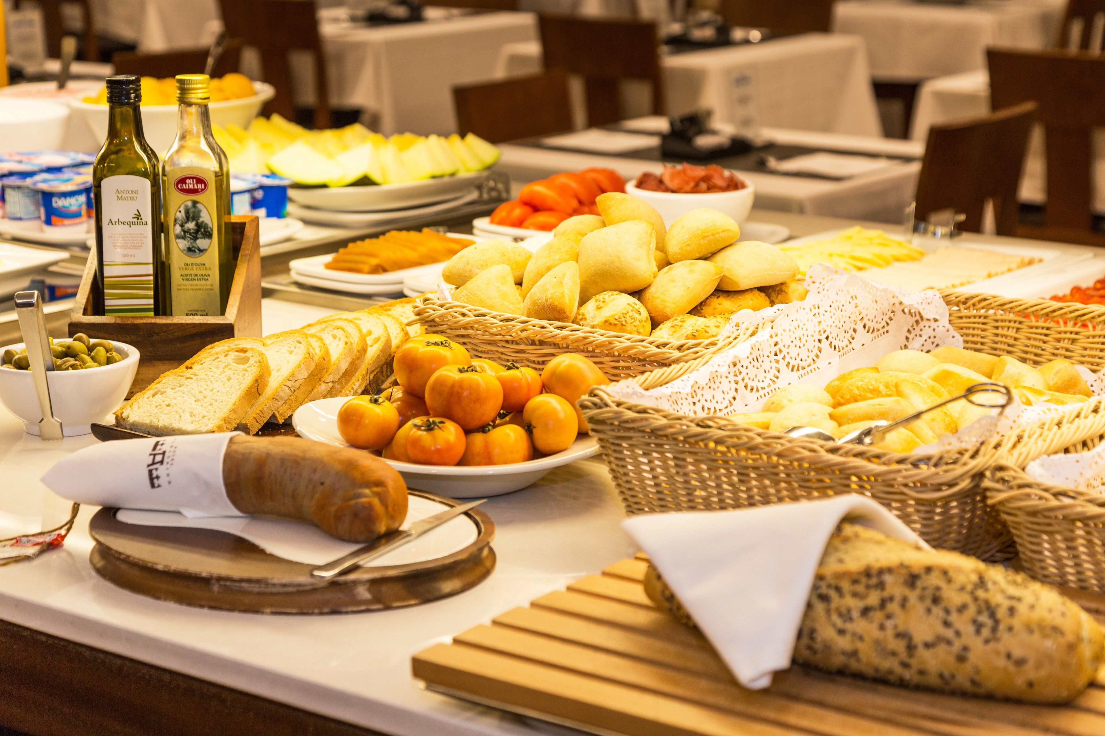 Une table de buffet proposant divers aliments, notamment du pain, des fruits et des condiments.