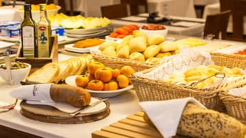 Une table de buffet proposant divers aliments, notamment du pain, des fruits et des condiments.