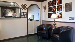 Un vestíbulo con dos sillones de cuero, un reloj de pared, obras de arte enmarcadas y una lámpara.
