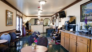 Un vestíbulo de hotel con zona de comedor, mostrador de recepción y cocina.