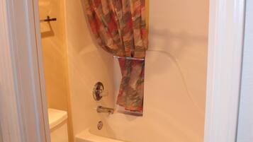 A bathroom with a toilet, bathtub, and shower curtain.