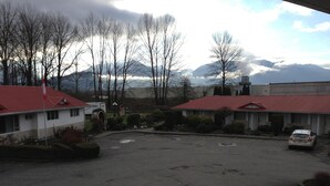 A parking lot with two-story buildings, a flag, and mountains in the background.