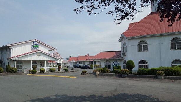 A motel with a red roof and white walls, featuring a sign for the Rainbow Motor Inn.