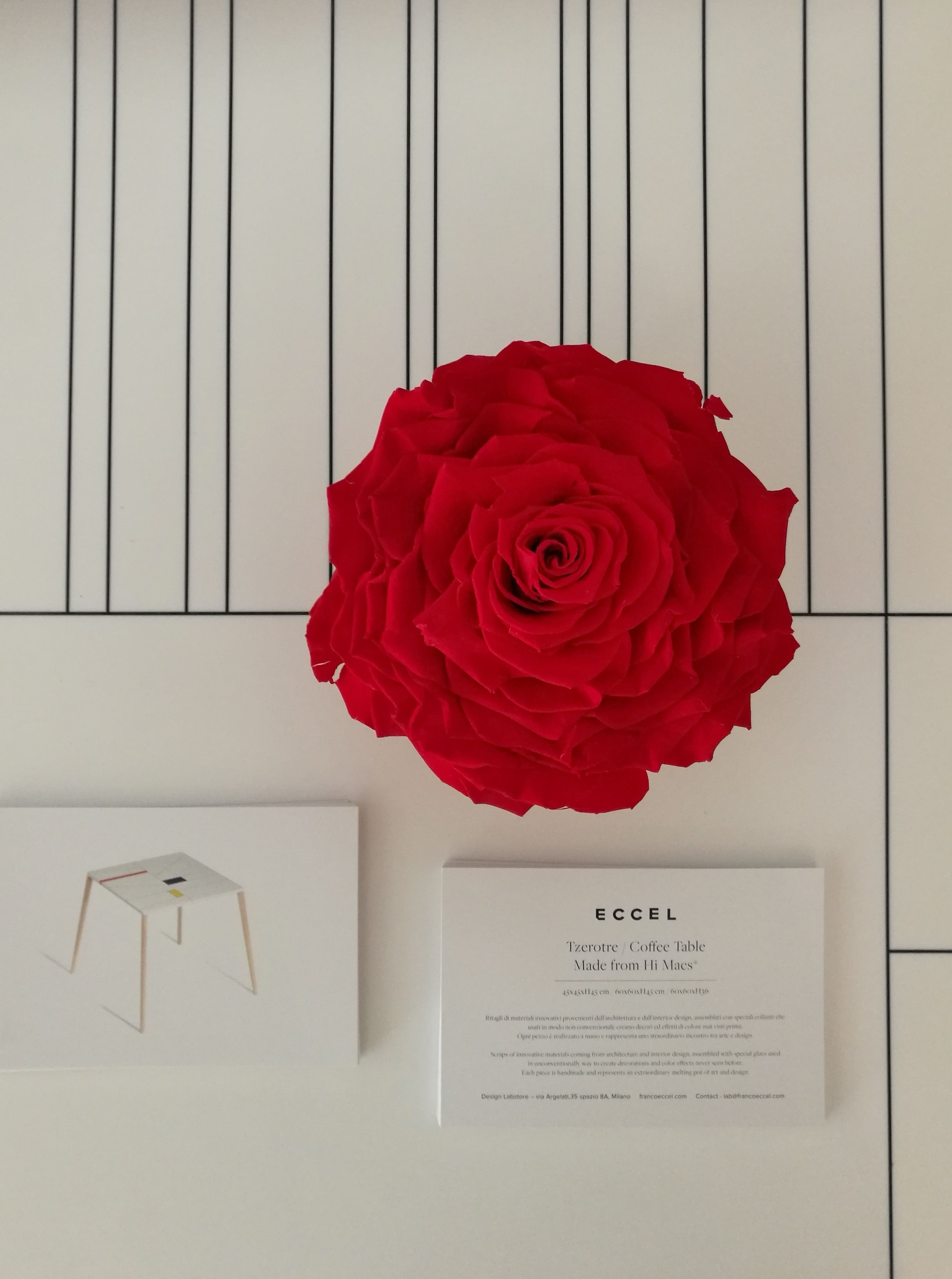 A red rose, a white coffee table, and a business card on a white background with black lines.