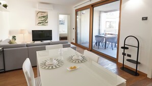 A modern living room with a sofa, TV, and dining table set with plates and cups. - Experience Design Bed & Show (Milan)
