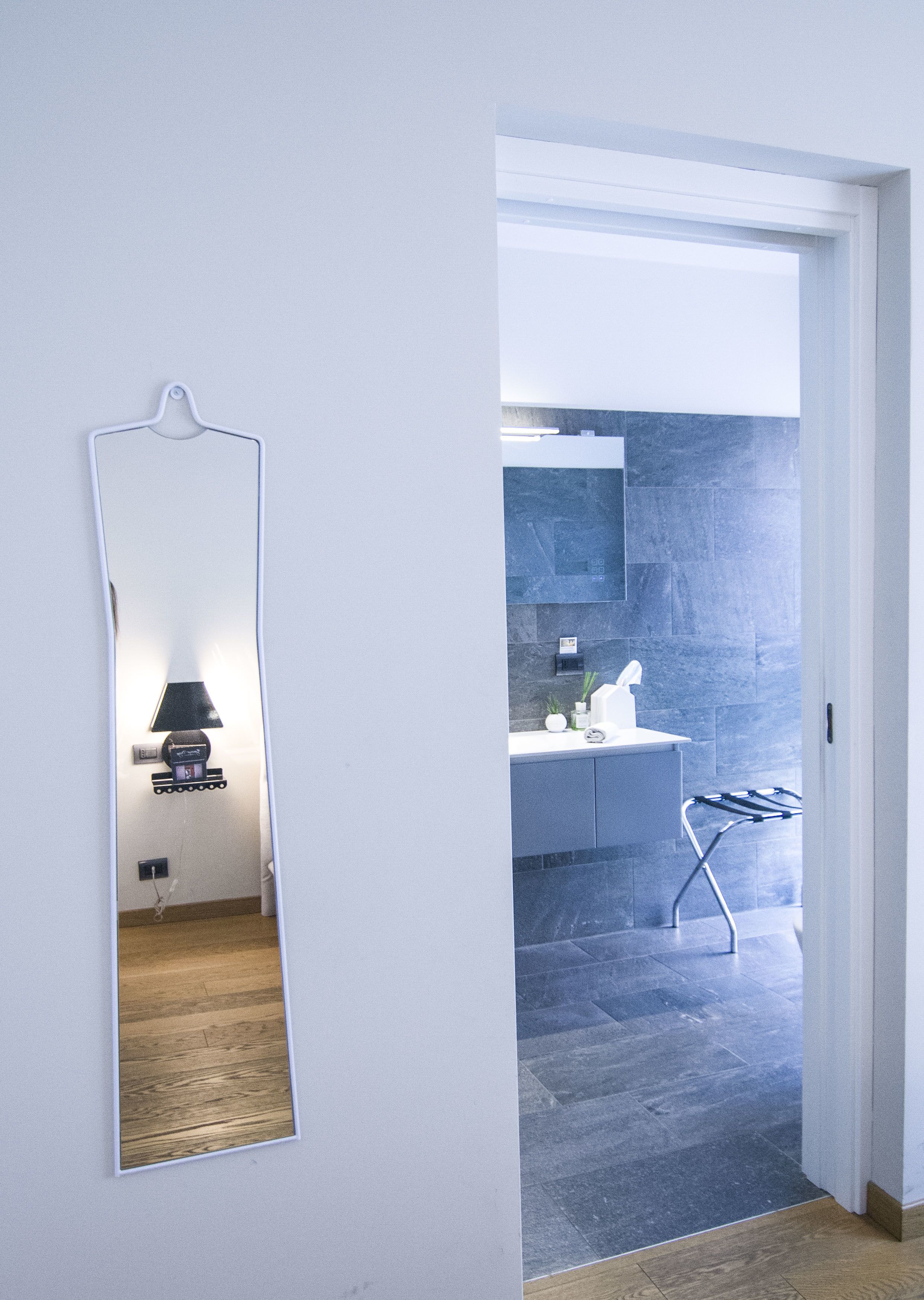 Un baño moderno con una pared de azulejos oscuros, un lavabo blanco y un perchero para toallas.