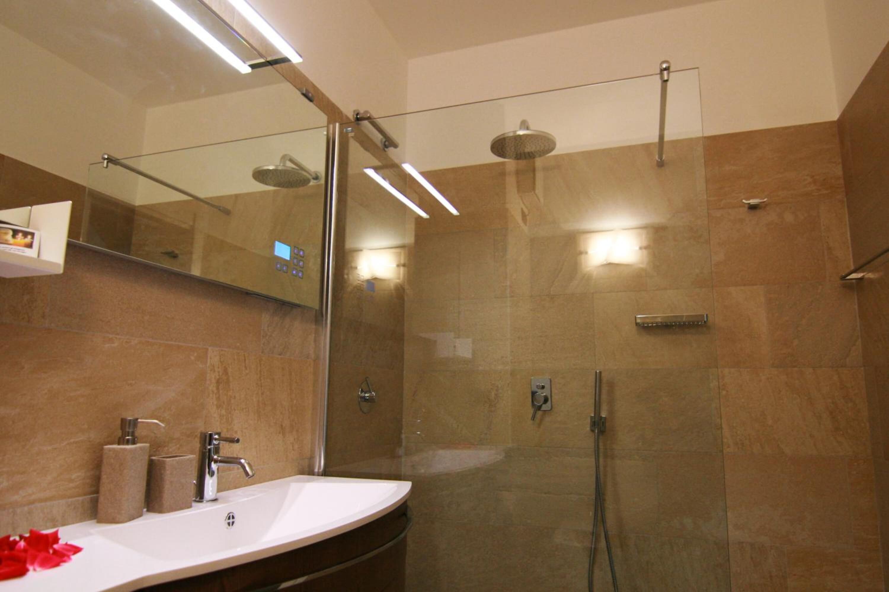 Een moderne badkamer met een douchecabine van glas, een wastafelmeubel met een wastafel en een spiegel.