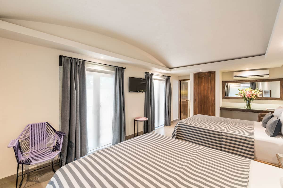 Habitación de hotel con dos camas, una silla, un televisor y un espejo.