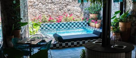 A pool area with a checkered floor, lounge chairs, and potted plants.