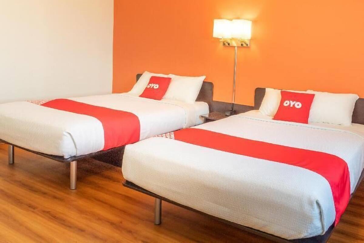 Two twin beds with red and white bedding, a standing lamp, and a wooden floor.