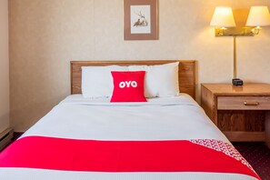 A hotel room with a bed, a nightstand, a lamp, and a framed picture on the wall. - OYO Hotel Shelby MT Hwy 2 & I-15 (Shelby)