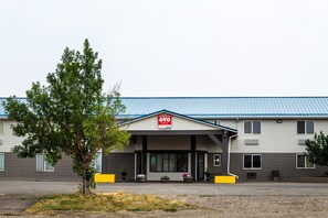 A hotel with a covered entrance, a signboard, and potted plants.