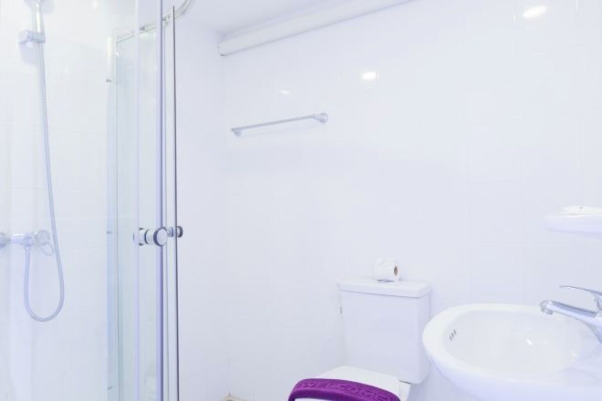 A bathroom with a glass shower enclosure, a white toilet, and a white sink.
