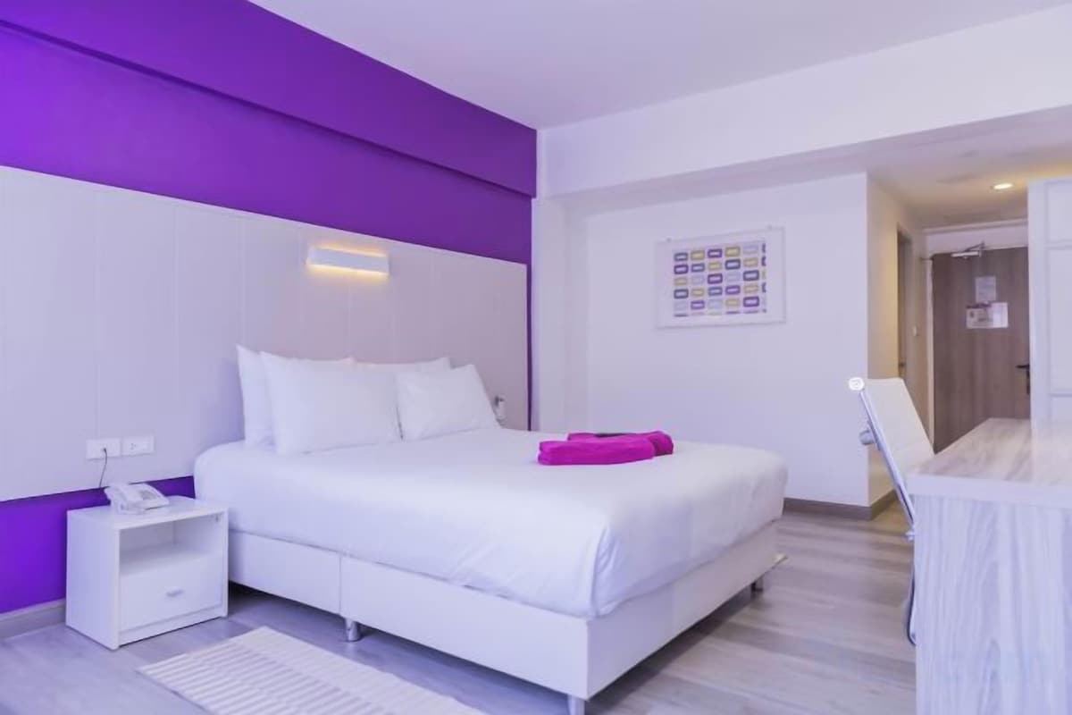 Un dormitorio moderno con una cama, una mesita de noche y un velador.