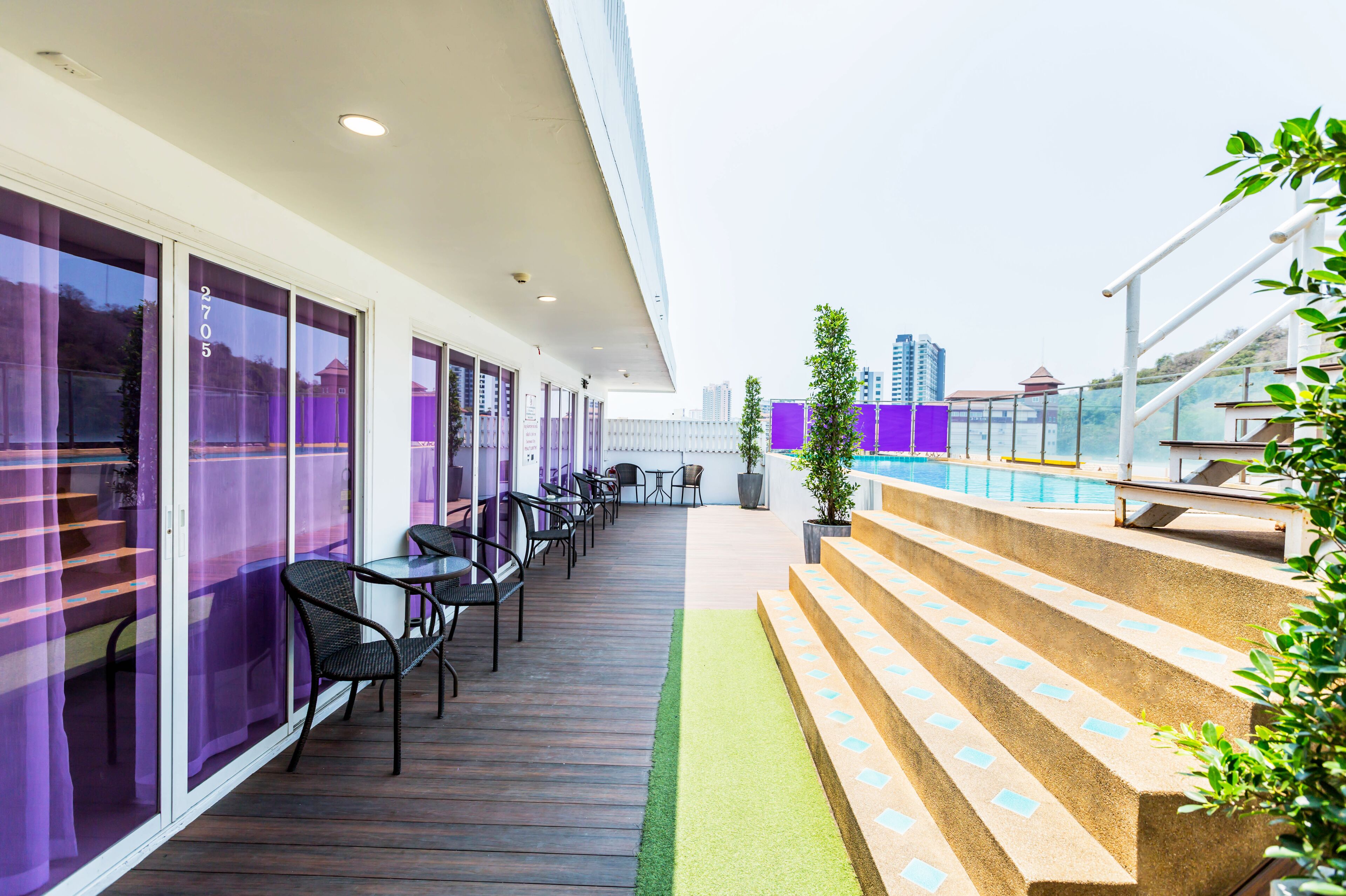 Um terraço com área de estar ao ar livre, piscina e escadaria para um andar superior.