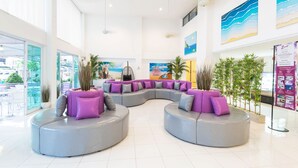 A modern lobby with a curved seating area, large windows, and artwork on the walls. - Hotel Zing (Pattaya)