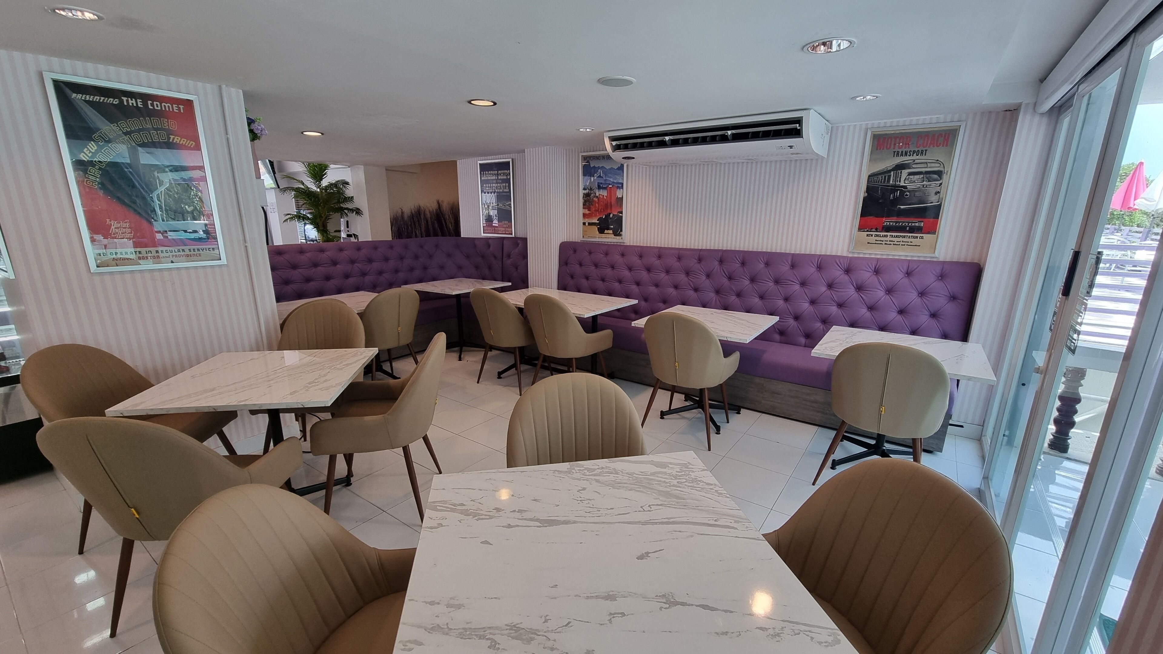 A restaurant with purple booths and beige chairs, marble tables, and posters on the walls.