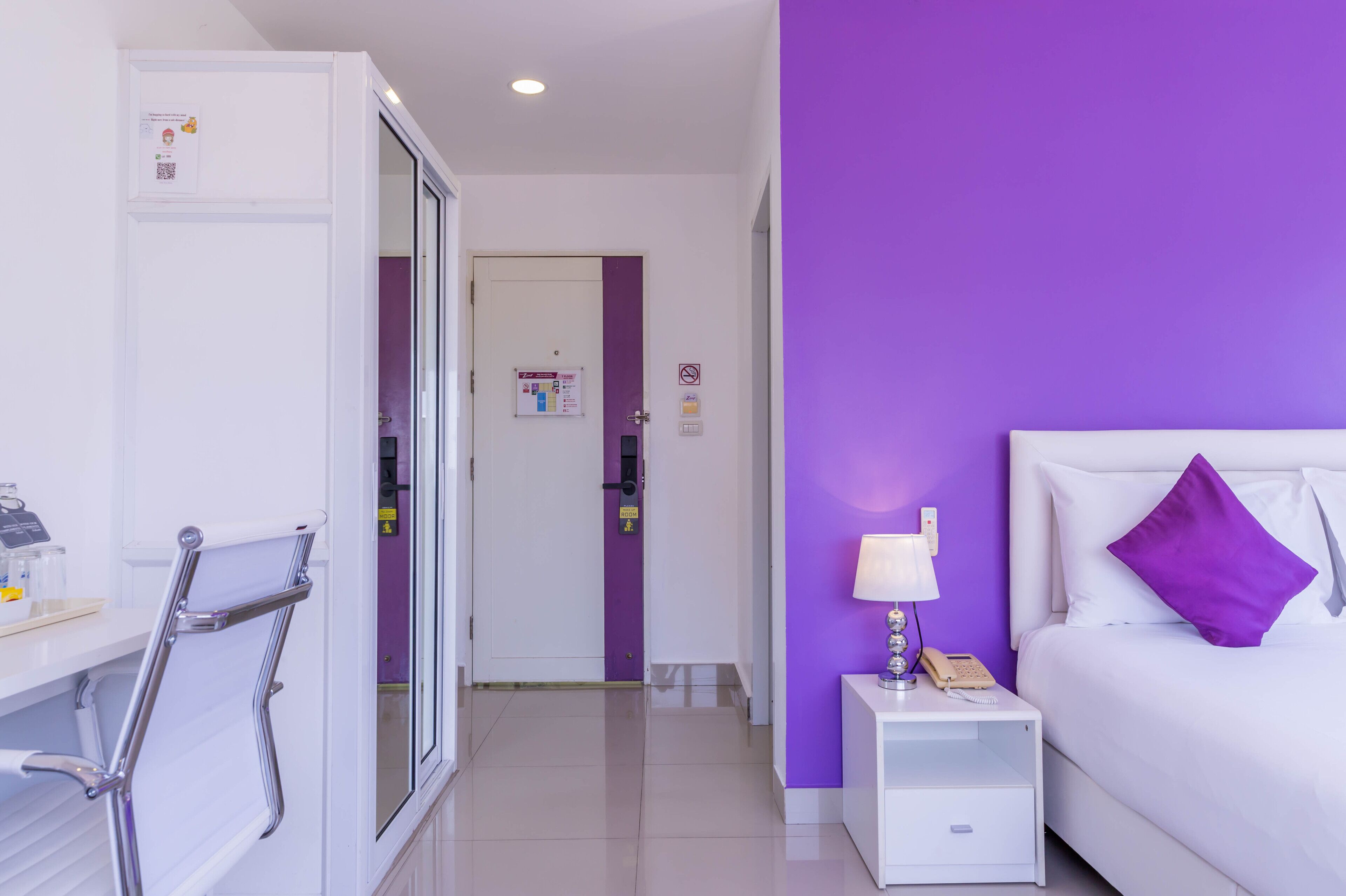 A hotel room with a bed, nightstand, and a bathroom with a towel rack.